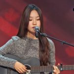 A 14-years-old takes the stage for a life-changing audition. Singing an acoustic cover of Like My Father, inspired by her parents, her impressive voice wows everyone. She earns a golden buzzer and